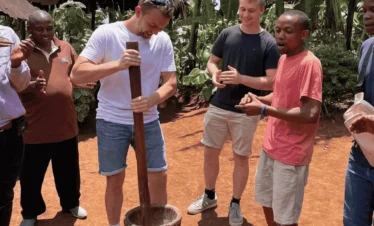 Men gather around a large pot on a fire and have lively conversations. Materuni Waterfalls day trip.